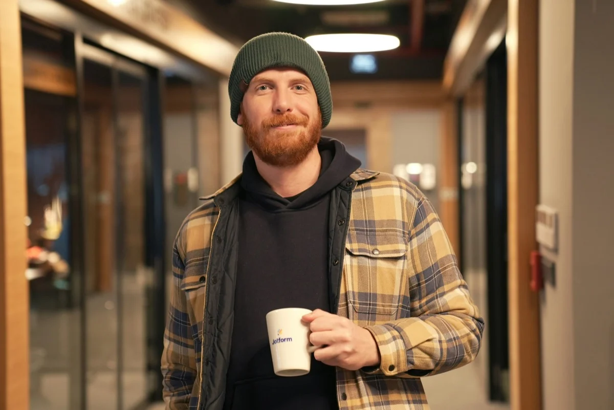 Developer holding a coffee mug in an office hallway
